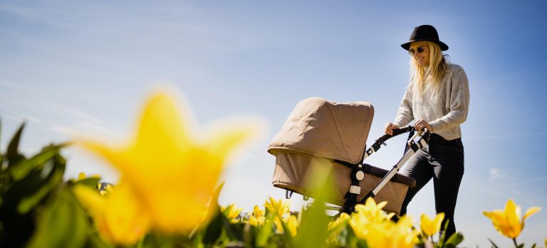 Mother with stroller outdoors among flowers