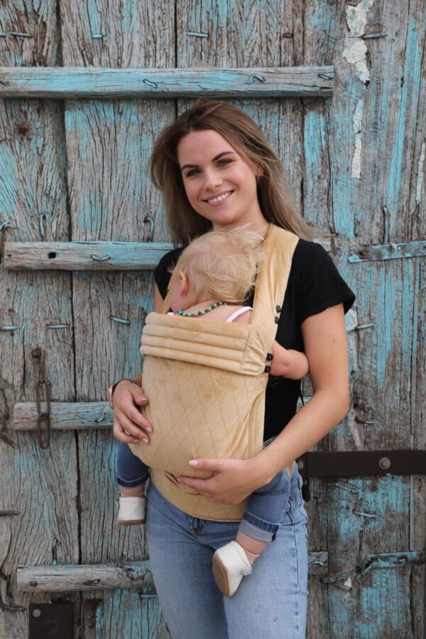 Moeder met baby in beige draagzak van fluweel met ruitjesmotief